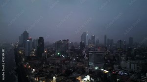 Aerial night view over Colombo, dense urban area glowing with life as traffic navigates city. Ocean waves crash against shore beside Sri Lankas lit high-rises, urbanization in South Asia.