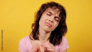 Beautiful woman begs that she does not want to do something. Attractive young girl on yellow background. High quality 4k footage