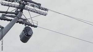 Moving gondola lift cable car system - aerial rope transit - low angle view. Overcast, grey sky. Tourism, sightseeing, public tansportation concept