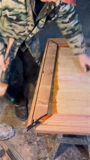 assembling a brown wooden frame by hitting the edges with a heavy hammer in a workshop today