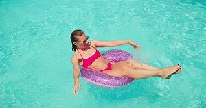 Pretty woman swim in the pool, sunbathes, swimming in hot summer day. Relax, Travel, Holidays, Freedom concept. Slim female relaxing along sea water waves on vacation