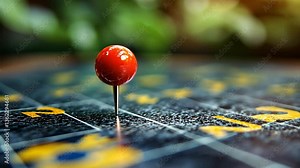 Close-up of a red pin marking a location on a weathered map with greenery