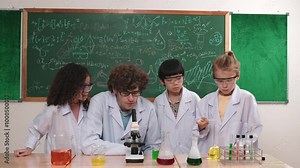 Smart caucasian teacher looking under microscope while diverse children doing experiment at STEM science lesson. Professional happy scientist inspect biochemical example by using microscope. Pedagogy.