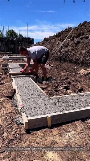 Construction workers use a board as a manual screeding tool to level concrete in formwork.