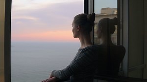 Closeup View Of Beautiful Young Woman Standing By The Open Window During The Sunset By The Sea And Enjoying The View | Free Stock Video Footage
