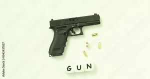 Handgun with bullets placed on table with cubes forming word Gun in shooting gallery. Weapon for military purposes prohibited to civilians