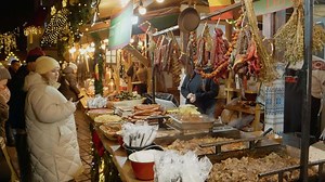 Download Crowds flock to a vibrant Christmas market, sampling a variety of meats including sausages and pork dishes while celebrating the holiday season with friends for free