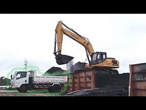 excavator dredging coal from barges, loaded onto trucks