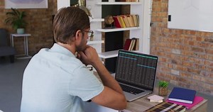 Caucasian man sitting at desk watching coding data processing on laptop screen. computer coding, data technology and digital interface concept digitally generated video.