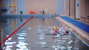 Swimming instructor teaching a kid how to swim in the pool