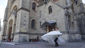 Groom spinning bride holding on his hands on wedding day at the church or castle