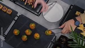 Appetizing and tasty snacks for guests, on a black table top view. Hands take snacks from the table decorated with palm leaves