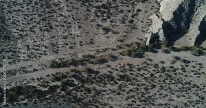 Aerial senital scene of desertic landscape. Moving over sparced shrub vegetaion discovering rocky mountains. Castelli, Rioja province Argentina. Cuyo