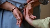 Close up man's hands being handcuffed behind his back/ zoom in cuffs