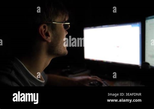 Focused trader analyzing cryptocurrency market trends on computer screen, illuminated by soft monitor light, showcasing intense concentration and strategic decision-making process in dark environment Stock Video Footage - Alamy