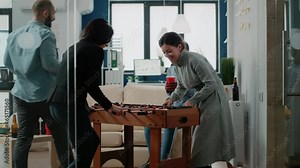 Happy women playing game at foosball table after work to do fun activity and leisure. Colleagues enjoying play while having beer drinks and snacks to celebrate party at office after hours