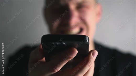 A man's angry face while yelling at someone on his smartphone. A man expressing emotion and yelling at someone while talking on the phone. Angry expressions and yelling