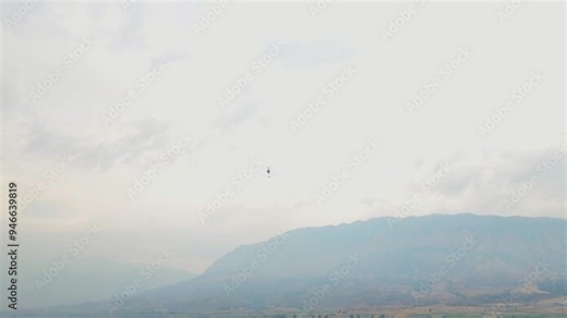 Helicopter with bucket attached for putting out wildfires flies away to fill up with water