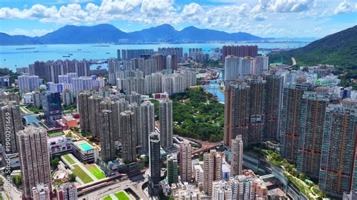 Aerial skyview of Tuen Mun subway extension project in Hong Kong, featuring elevated railway construction along Tuen Mun River and road, new station development and temporary work platforms