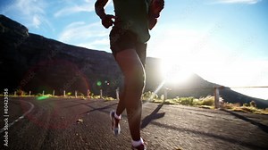 Running feet of male runner on mountain road in slow motion