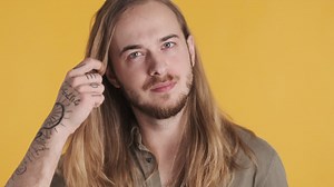 Free stock video - Caucasian young man preening his hair in front of the camera.