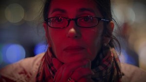 A thoughtful and contemplative woman is beautifully illuminated by red light at night