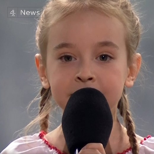 Seven-year-old Amelia Anisovych - who went viral after singing the Frozen hit song 'Let It Go' in a bunker in Kyiv - performs the Ukrainian national anthem at a charity concert in Poland for victims of the war. | Channel 4 News