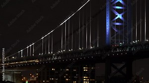 The metro crossing the Ben Franklin Bridge in Philadelphia at night with the lights shining.