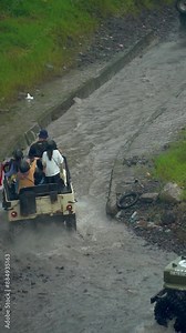 Off-road footage of a tourist Jeep driving across a river at such high speed that water splashes in all directions and wets its passengers. An adrenaline-pumping journey by driving an offroad jeep
