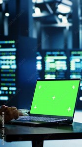 Vertical video Asian technician using mockup laptop to implement artificial intelligence parallel processing. Specialist works on chroma key device enabling AI systems to do machine learning inference