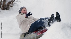 Cheerful smiling elderly mature woman riding on snow tubing. Senior lady sledding slide down hill. Winter fun activity outdoor. Young at heart concept.
