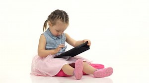 Baby is holding a computer in her hands and cliches, she is in a good mood. White background