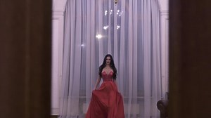 A tall girl model in a red dress and long hair opens the door to an 18th-century mansion in the center of Moscow.