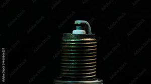 Spark plug generates a vibrant blue and yellow spark against a black background. The isolated component highlights the intricate details of ignition technology in automotive applications