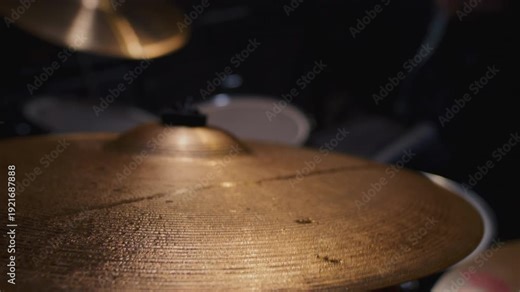 Water drops flying from drum kit. Drum player hits the cymbals of the drum set powerfully during the rock show on a stage under strobe flashes close up. Drummer playing the drums with drumsticks