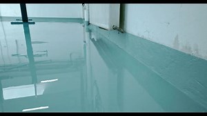 Epoxy floor Construction worker spreads blue epoxy resin on a concrete floor