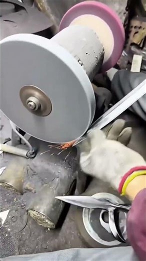 sharpening a metal sword blade with a rotating grinding wheel and creating sparks