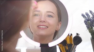 Beauty model girl looking in the mirror and applying foundation with a cosmetics sponge make up. Beautiful young woman apply makeup. Make-up routine. Slow motion 240 fps. 4K UHD video