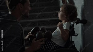 Young father taking care of his disabled child on a wheelchair