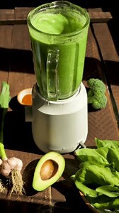 Vertical: blending a green vegetarian vegetable smoothie consisting of broccoli, avocado, spinach and garlic in a blender. Making a green vegan smoothie. Veganism and diet. Vertical video