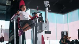 Crossfit training. asian sport female doing abdominal exercise with rising up her leg with machine. Functional training workout, personal circuit training, fitness class
