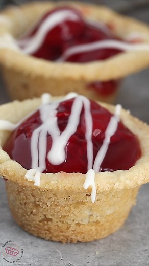 Cherry Pie Cookie Cups taste like mini cherry pies with a sugar cookie crust! This is an easy recipe you can make with four ingredients. The cookie cups are filled with cherry pie filling and topped with a simple glaze. Get the full recipe here: https://www.crazyforcrust.com/cherry-pie-cookie-cups-recipe/ | CrazyforCrust