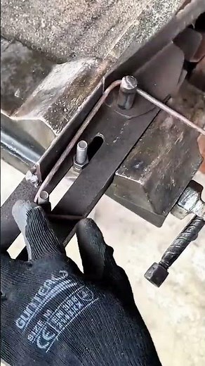 Bending a long thin metal rod into a rectangular shape using a manual metal bending tool in workshop