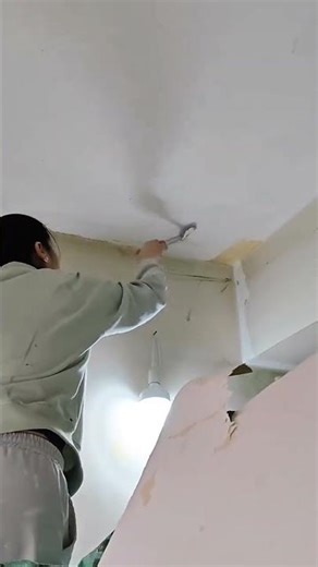 applying white paint to the ceiling using a small brush to cover the edges and corners neatly