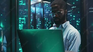 African american young IT professional inspecting a rack server cabinet using a laptop computer running diagnostic or backup operations working at data center.