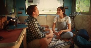 Young Loving Couple Sitting on a Bed, Talking and Joking Around in a Cozy Motorhome. Adventurous Man and Female Travelling, Camping in a Caravan and Enjoying Boho Lifestyle. Recreation and RV Life.