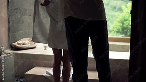 Young woman taking off towel and walking into bath in bathroom