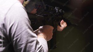 Man firing an assault rifle in a shooting range with the shell jumping in slow motion.