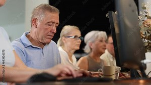 Computer lessons for elderly people in a nursing home. Group of seniors learning to use computers in class