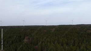 Aerial view of wind farm turbines set up in countryside with forest. Producing power using energy of nature. Incorporating technology into environment of nature. Cloudy sky. Electricity production.